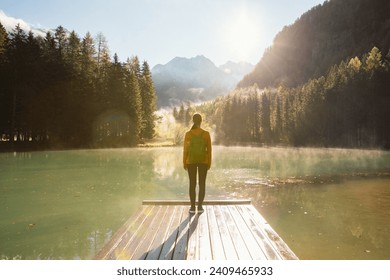 Young woman standing at the edge of a wooden pier at a mountain lake. Amazing autumn scenery. Young female backpacker in Europe.  - Powered by Shutterstock