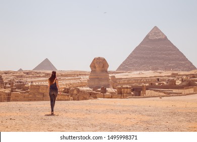 Joven parada frente a la Gran Esfinge de Giza con las sorprendentes pirámides en la parte trasera. Valle de los Reyes, El Cairo, Egipto. 