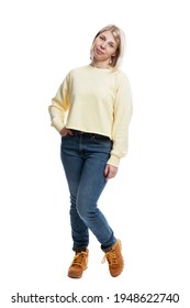 The Young Woman Is Standing. Full Height. Blonde Girl In Jeans And A Yellow Sweater. Vertical. Isolated On A White Background.