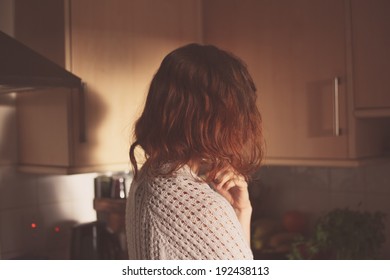 A Young Woman Is Standing At Home In Her Kitchen And Thinking