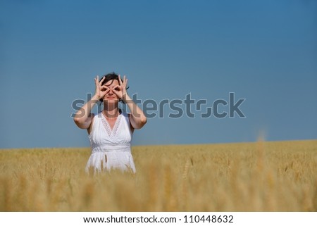 Similar – Junge Frau bedeckt ihr Gesicht vor der Sonne auf einem grünen Feld.