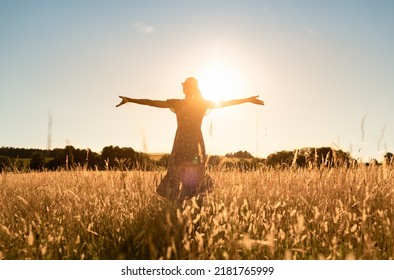 Young woman standing in a meadow feeling happy and free with open arms up to the warm sunlight. Feelings of peace and happiness concept.  - Powered by Shutterstock