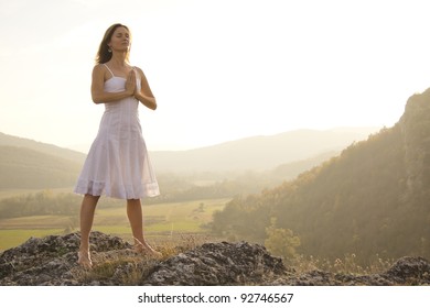 Young woman standing in meditation on the top of a hill