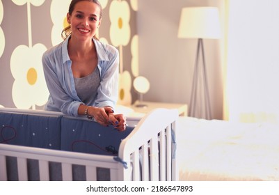 Young Woman Standing Near Children's Cot. Young Mom