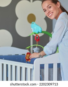 Young Woman Standing Near Children's Cot. Young Mom