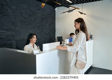 Young woman standing near customer service counter - Powered by Shutterstock