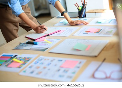 Young woman standing near desk with instruments, plan and laptop - Powered by Shutterstock