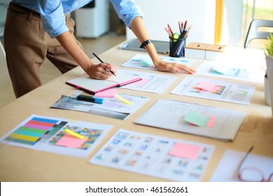 Young woman standing near desk with instruments, plan and laptop - Powered by Shutterstock