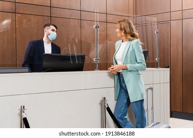 Young Woman Standing Near Hotel Manager In Medical Mask In Lobby