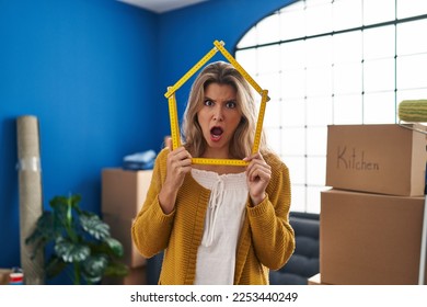 Young woman standing at new home in shock face, looking skeptical and sarcastic, surprised with open mouth  - Shutterstock ID 2253440249