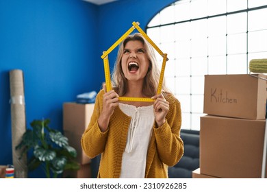 Young woman standing at new home angry and mad screaming frustrated and furious, shouting with anger looking up.  - Shutterstock ID 2310926285