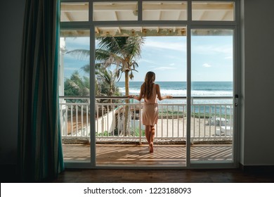  Young woman standing on the balcony and looking at the sea view. Vacation on tropical island, Sri Lanka