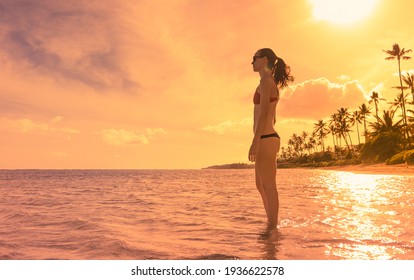 Young woman standing on a beach enjoying beautiful sunny weather. People travel, and tropical island getaway concept. 