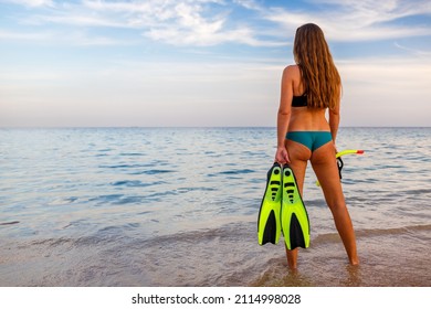 Young Woman Standing On The Cliff And Holding A Mask And Snorkel. Snorkeling Or Scuba Diving Tropical Vacation Background.