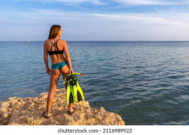 Young Woman Standing On The Cliff And Holding A Mask And Snorkel. Snorkeling Or Scuba Diving Tropical Vacation Background.