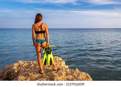 Young Woman Standing On The Cliff And Holding A Mask And Snorkel. Snorkeling Or Scuba Diving Tropical Vacation Background.