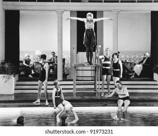 Young Woman Standing On A Diving Board Surrounded By A Group Of People Playing