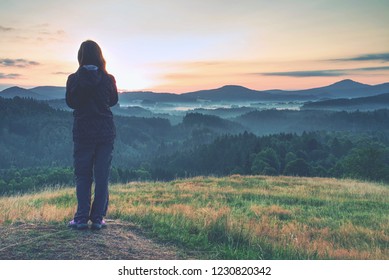 Young Woman Standing On Golden Meadow And Watching Towards The Sunrise Above Mist.