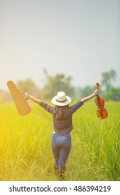 young woman standing on rice field with violin