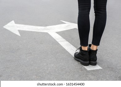 Young Woman Standing On Road With Arrows Marking. Concept Of Choice