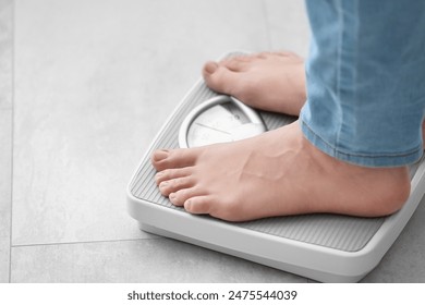 Young woman standing on scales at home, closeup. Weight loss concept