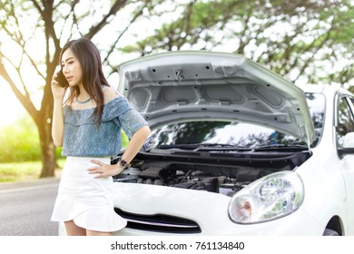 Young woman standing on the side of the road with broken car and calls the evacuation service