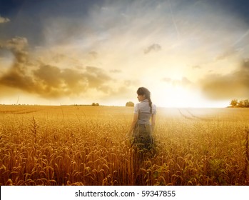 Young woman standing on a wheat field with sunrise on the background - Powered by Shutterstock
