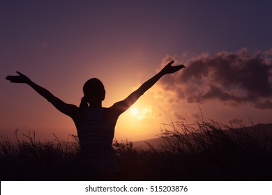 Young Woman Standing In A Open Field With Her Arms Raised Up In The Air Feeling Happy And Free. 