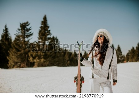 Young woman standing with skis on the ski track at a sunny day