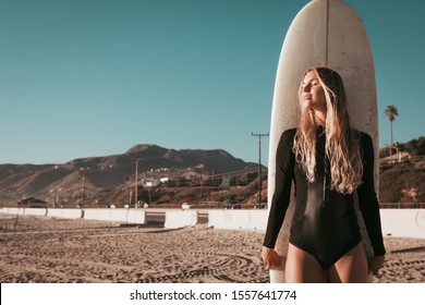 Young Woman Standing With Surfboard At Malibu Beach