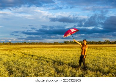 Young woman standing with an umbrella looking at the sky and the beautiful meadow - Shutterstock ID 2236328205