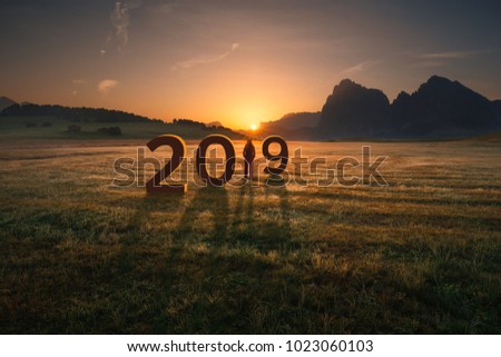 Young woman standing and watching the rising sun, uncertainty for upcoming 2019 new year. Future and time passing concept.