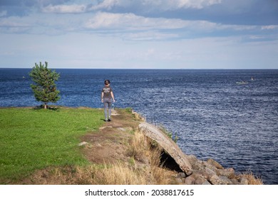 A young woman stands alone on the rocky shore of the lake. Shlisselburg, Lake Ladoga. - Powered by Shutterstock