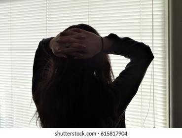 A Young Woman Stands By A Window