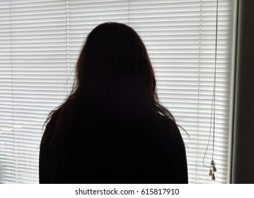 A Young Woman Stands By A Window