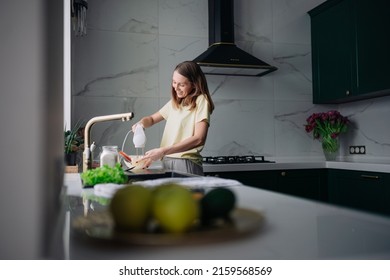 A young woman stands in the kitchen and cooks food with an electric mixer