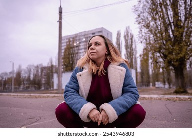 A young woman stands near a chain-link fence in an urban area during the late afternoon of an autumn day. - Powered by Shutterstock