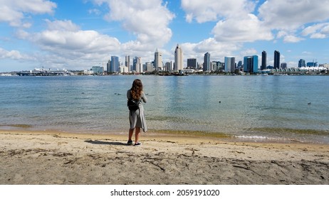 A Young Woman Stands On The Beach Of The San Diego Bay.