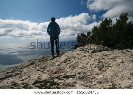 A young woman stands on the edge of a cliff and admires the view of the Black sea, Crimea, Russia.