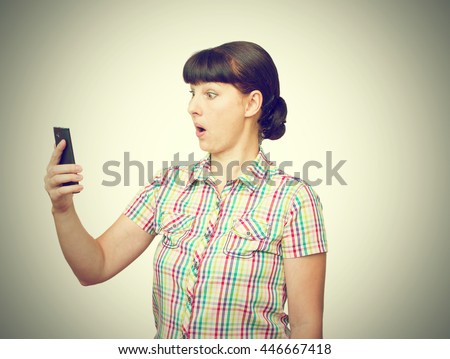 The young woman stares at the phone screen. Isolated on a white background.