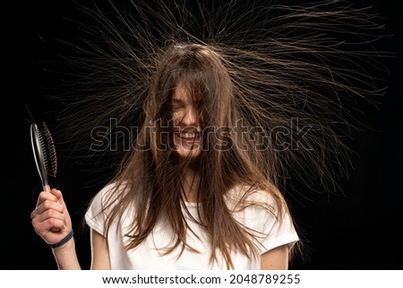 Young woman with static long hair up, on black background. 