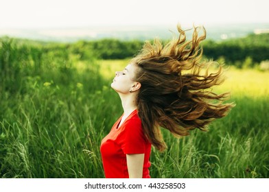 Young Woman Stay Is Burned Field. Woman Stands Facing The Camera And The Visible Light Leak.  Portrait Of A Young Beautiful Girl On A Background Of Nature