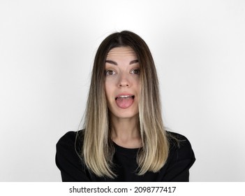 Young Woman Sticking Out Tounge, Close Up Portrait. Teasing You Through Camera While Isolated With White Background. It Looks Like She Doesn’t Have Arms.