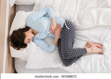 Young Woman With Stomach Ache Lying On Bed - Shutterstock ID 393388072