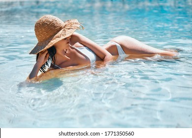 Young Woman In Straw Hat And White Bikini Relax In Turquoise Sea On Tropical Paradise Beach. Summer Vacation, Travel Destination, Holiday Concept                        