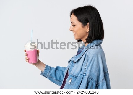 Young woman with strawberry milkshake isolated on white background with happy expression