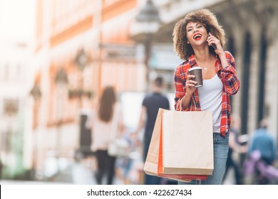 Young woman at the street with shopping bags talking on mobile phone
