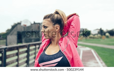 Young woman stretching arms before training outdoors