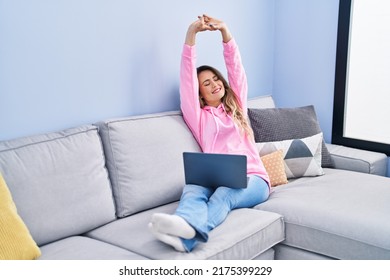 Young Woman Stretching Arms Using Laptop At Home