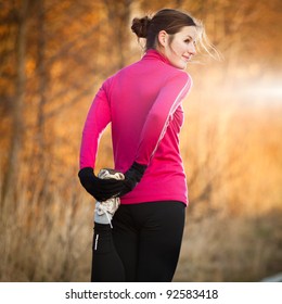 Young Woman Stretching Before Her Run Outdoors On A Cold Fall/winter Day